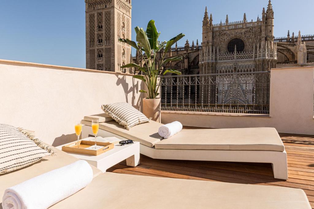 2 camas en un balcón con una torre del reloj en Puerta Catedral Apartments, en Sevilla