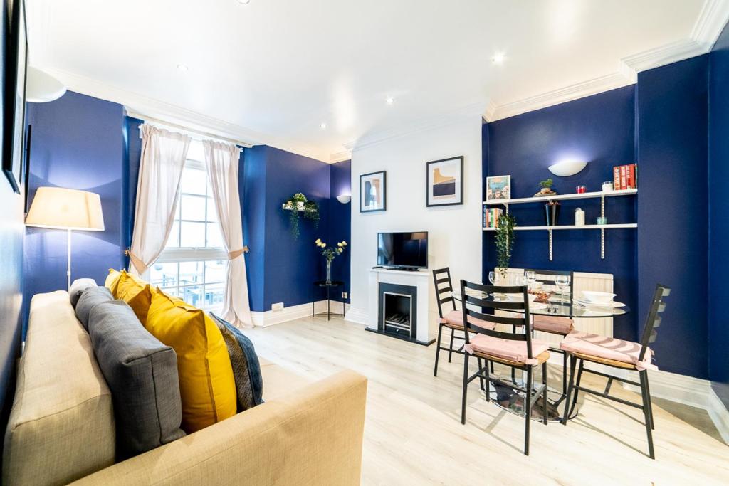 ein Wohnzimmer mit blauen Wänden, einem Sofa und einem Tisch in der Unterkunft ［Regent' S Park-Fitzrovia］Central London Apartment in London
