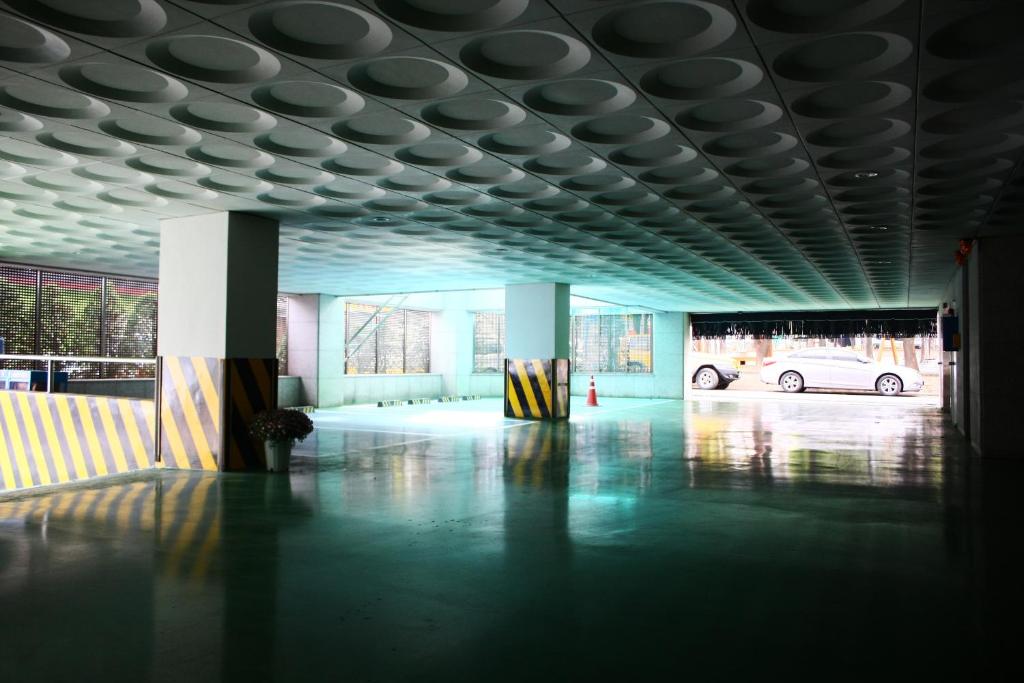 a building with a car parked in a parking lot at Metro Pol Tourist Hotel in Pyeongtaek