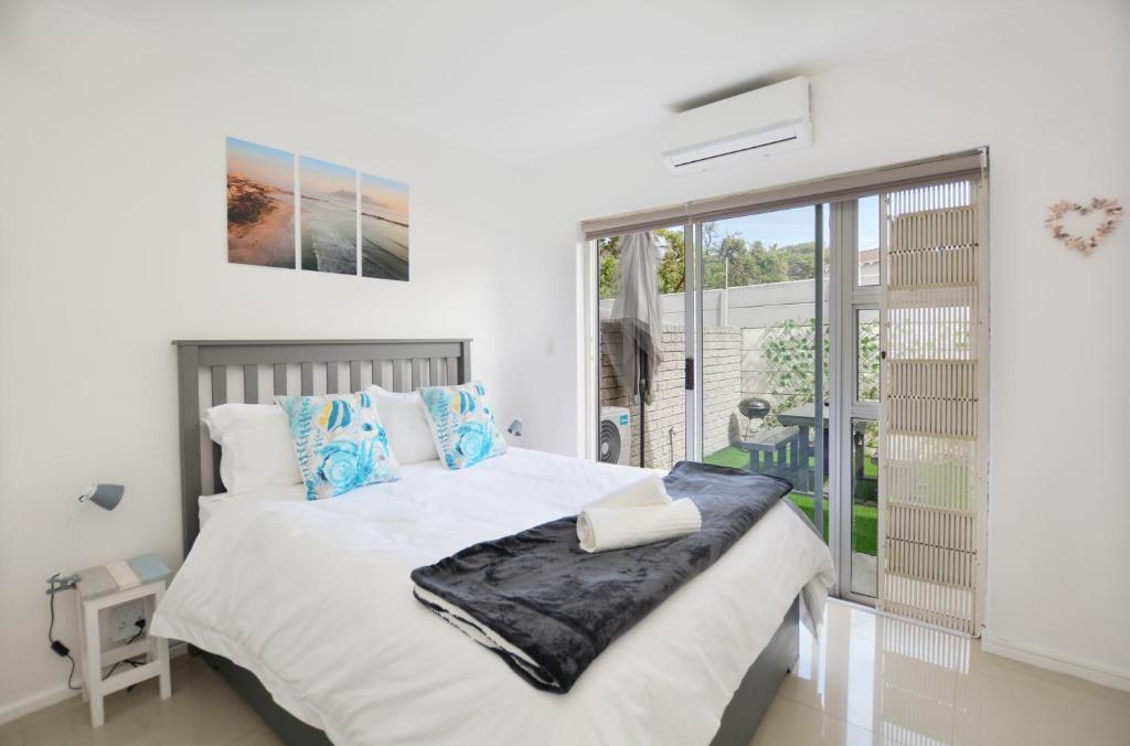1 dormitorio con cama blanca y almohadas azules en Say Shells, en Ciudad del Cabo