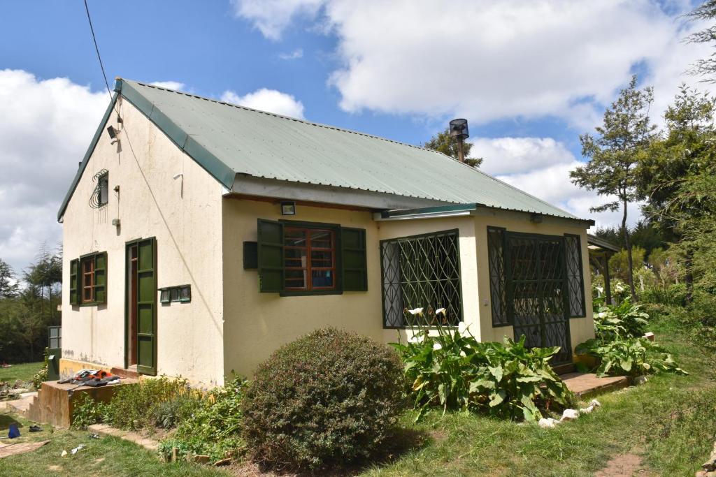 Comfortable countryside retreat for the family. في Kijabe: منزل أبيض صغير ذو سقف أخضر