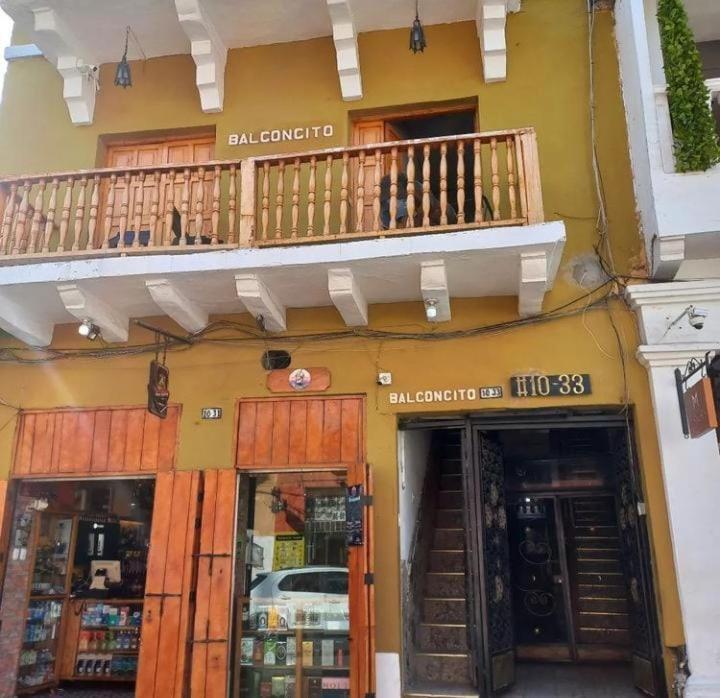 un edificio amarillo con balcón y 2 tiendas en Hostal #10-33 en Cartagena de Indias