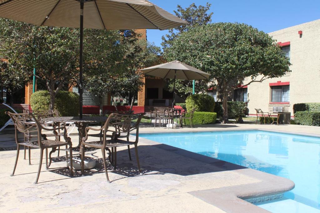 a table and chairs with an umbrella next to a pool at Casa Grande Chihuahua in Chihuahua