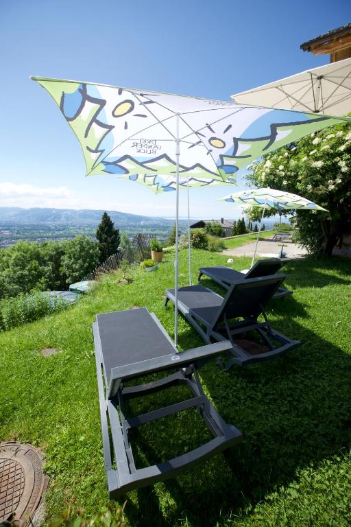 2 chaises longues et un parasol sur l&#39;herbe dans l&#39;établissement Hotel Dreiländerblick Dornbirn, à Dornbirn