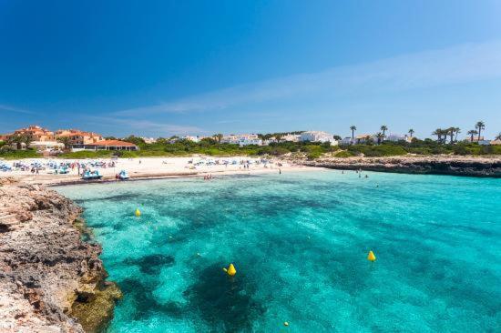 a beach with a group of people in the water at Precioso apartamento de dos hab. en Calan Bosch in Ciutadella