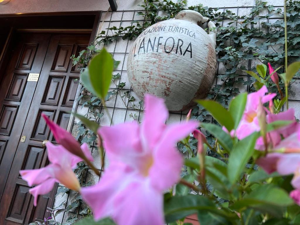 un pot sur le côté d'un bâtiment avec des fleurs roses dans l'établissement L' anfora Locazione Turistica, à Terni