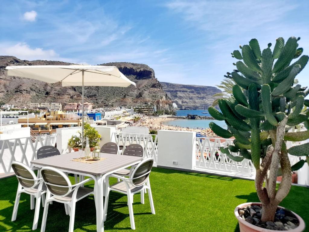 a white table and chairs and a cactus on a patio at Malibú Mogán Casa Vintage - Amazing sea/harbour view in Puerto de Mogán