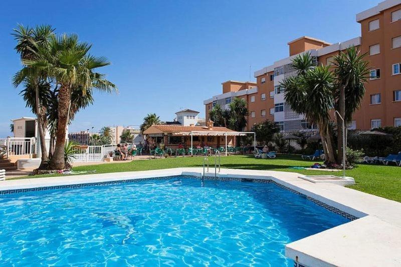 une grande piscine bordée de palmiers et un bâtiment dans l'établissement Lovely apartment in Torremolinos, à Torremolinos