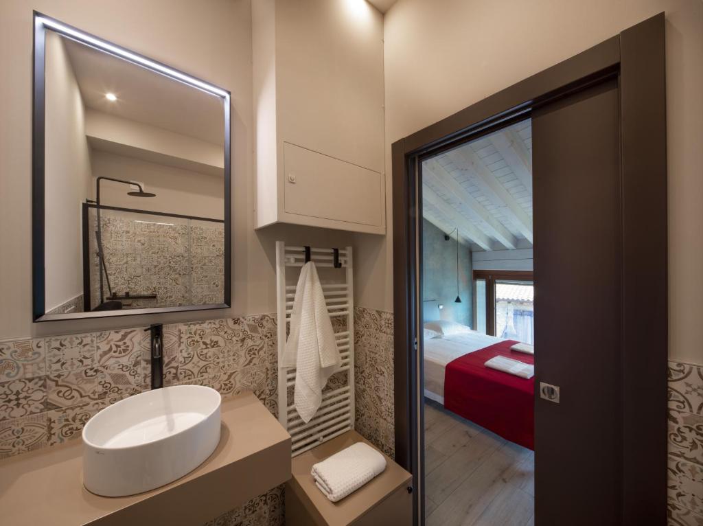 baño con lavabo, espejo y cama en Monte Isola - Decio Rooms en Monte Isola
