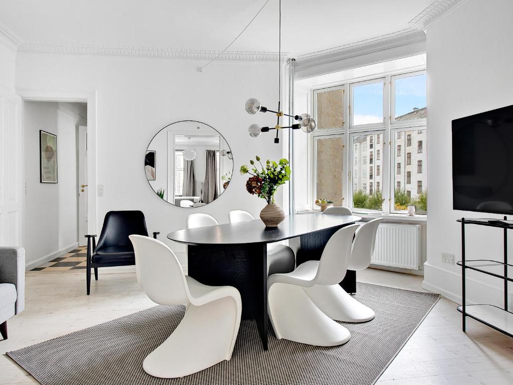 Sanders Stage - Perfectly Planned Three-Bedroom Apartment Near Nyhavn في كوبنهاغن: غرفة طعام مع طاولة سوداء وكراسي بيضاء