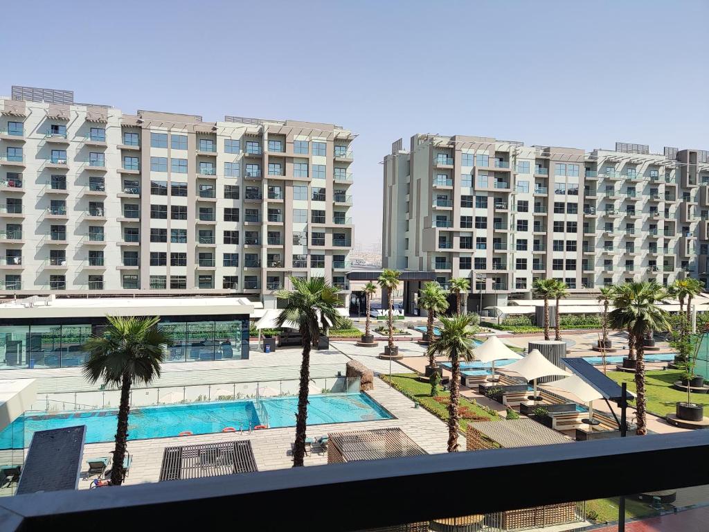 a view of a resort with a pool and palm trees at 5*Amenities-2Br-15 min DxbApt,20min to Dubai Mall in Dubai