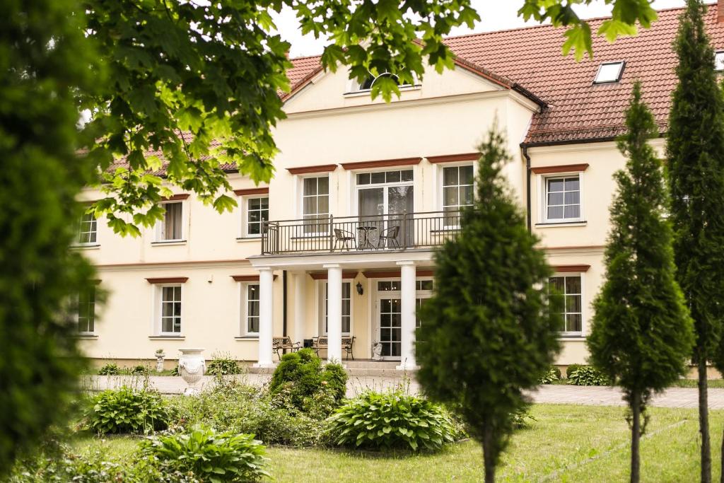 a large white house with trees in the foreground at Ziemupes Muiža & SPA in Ziemupe
