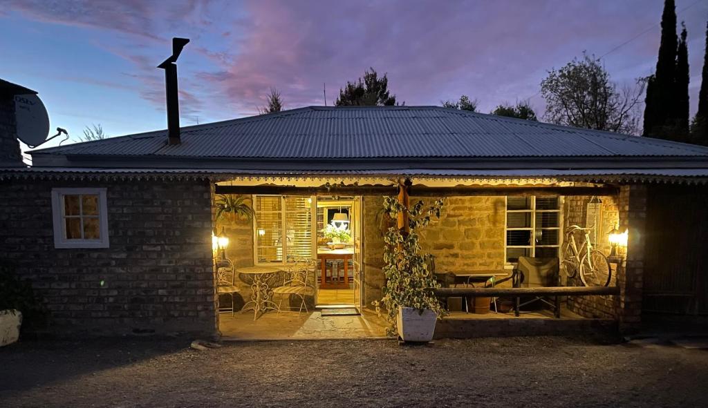 a brick house with an open door with a patio at Ou Klipskuur Self-Catering Accommodation in Fraserburg