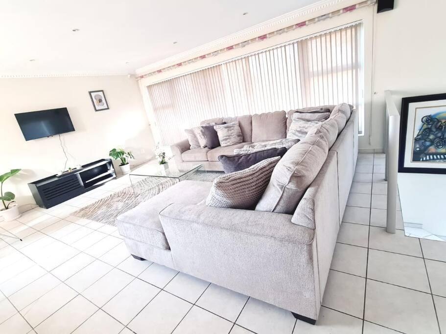 a living room with a couch and a tv at Luxurious Pvt Apartment ,Power backup, Pool & Jaccuzi in Sandton