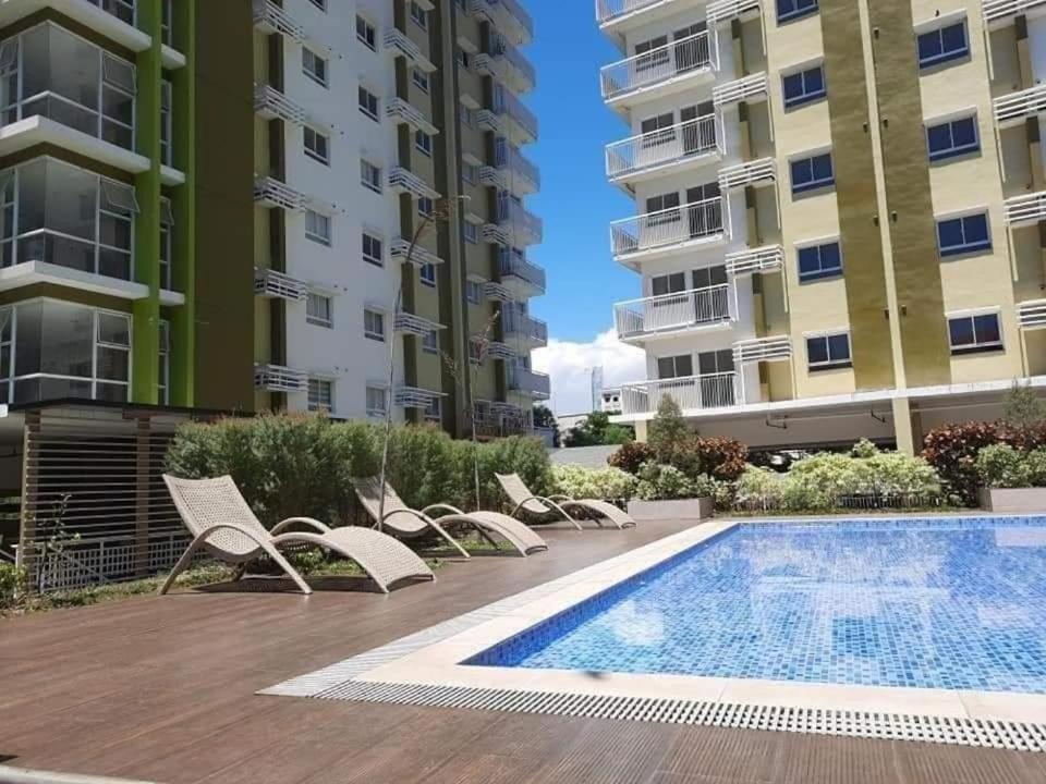 a swimming pool in a apartment with chairs and a building at Cozy Mesaverte Condo Residences in Cagayan de Oro