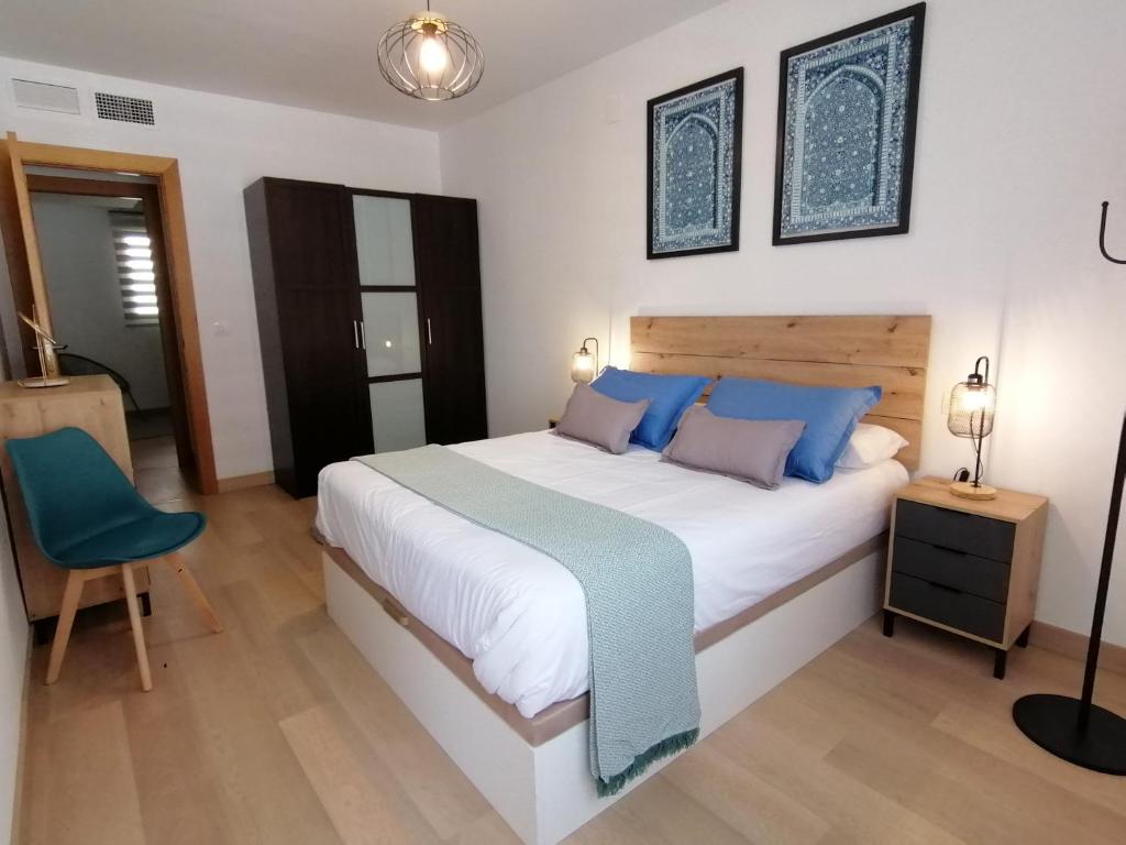 - une chambre avec un lit et une chaise bleue dans l'établissement Relax & home, apartamento con terraza y parking, à La Zubia
