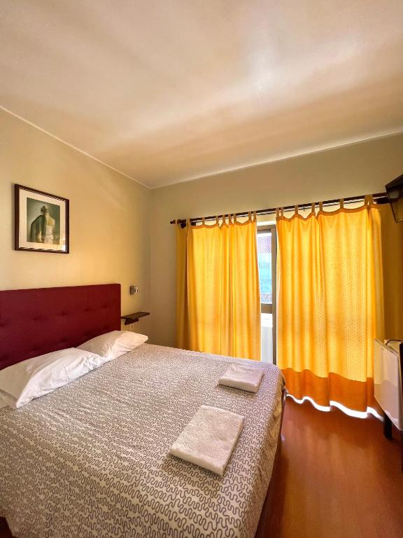 1 dormitorio con 1 cama y una ventana con cortinas amarillas en Abrigo do Portinho, en Vila Praia de Âncora