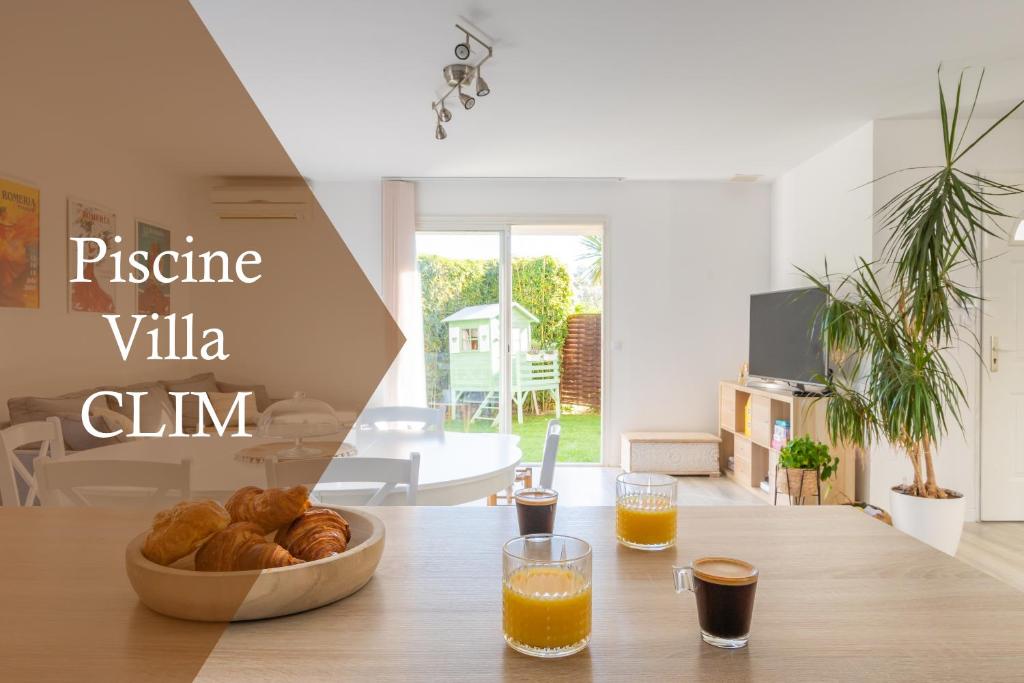 uma mesa com uma tigela de pão e dois copos de sumo de laranja em Maison familiale avec piscine em Mauguio