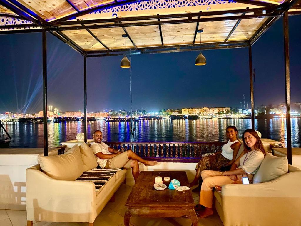 a group of people sitting on a porch with a view of the water at Nile Castle in Luxor