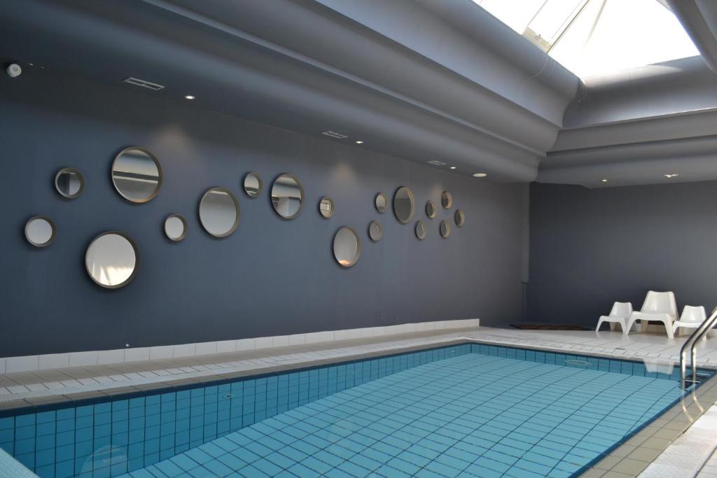 a swimming pool in a room with mirrors on the wall at Logis Hôtel Restaurant Le Calluna in Préfailles