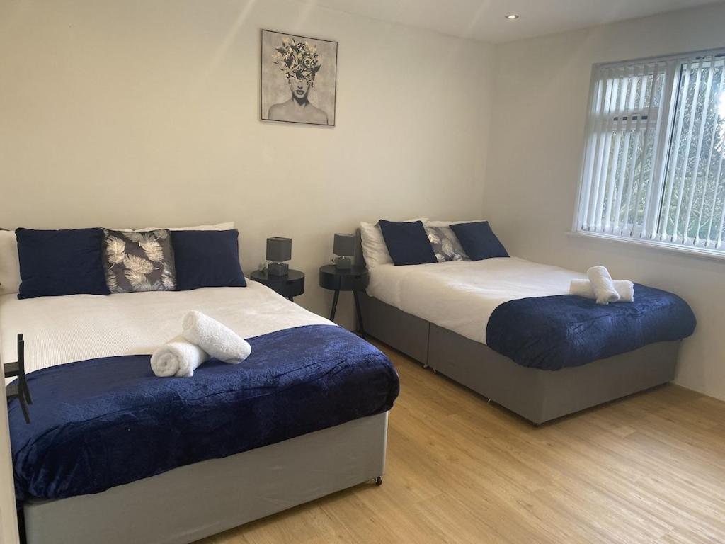 a bedroom with two beds with blue and white sheets at PRIVATE•ASTONISHING•CONTRACTOR•DETACHED•LutonAirport•WI-FI•PARKING•SPACIOUSNESS in Luton