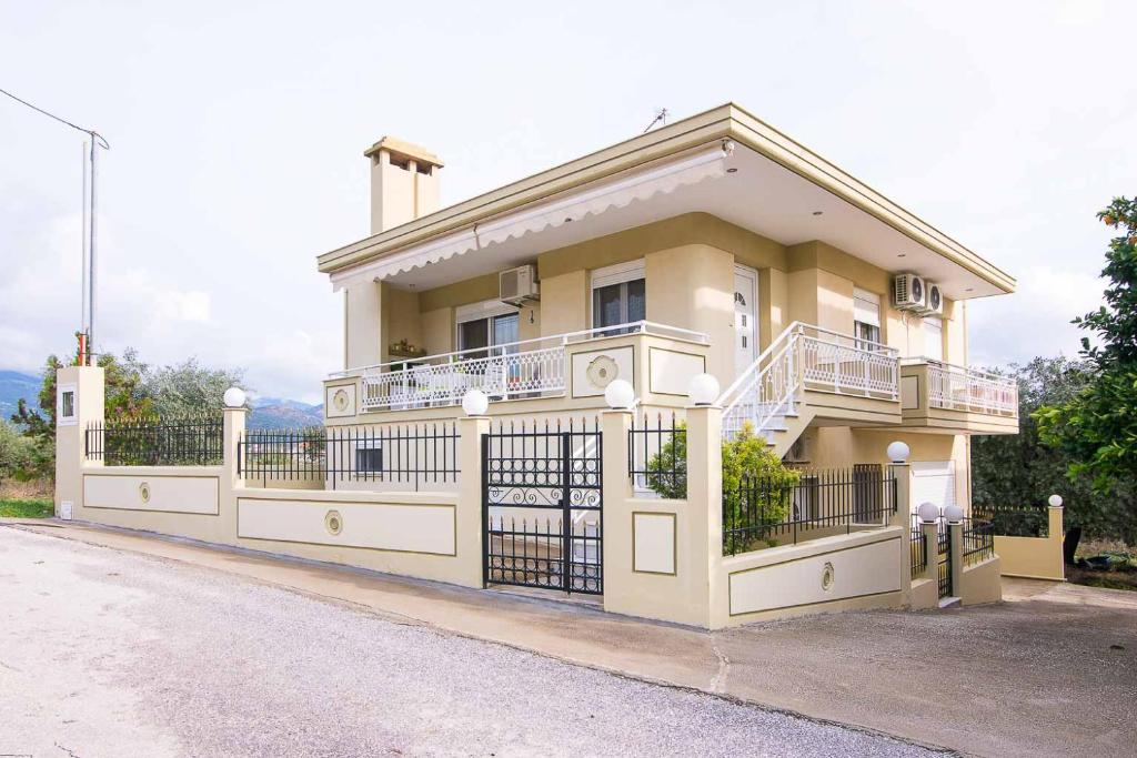 a large yellow house with a fence in front of it at Villa Evdokia in Limenaria