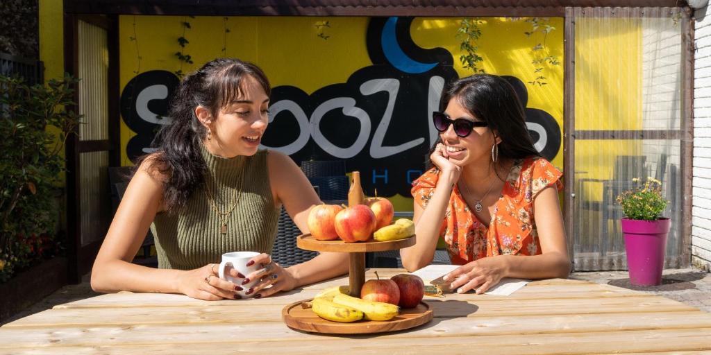 duas mulheres sentadas numa mesa com um prato de fruta em Snoozles Galway City Centre em Galway