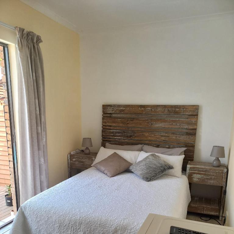 Schlafzimmer mit einem Bett mit einem Kopfteil aus Holz in der Unterkunft Lime Court Four in Pretoria