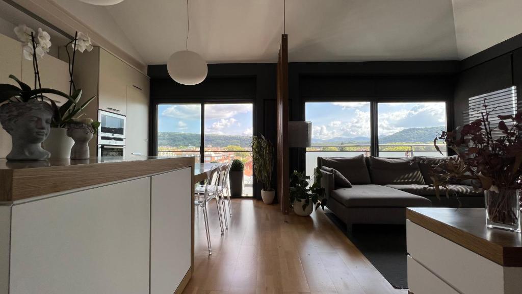 a kitchen and living room with a couch and windows at Ático de diseño con terraza en el centro de Olot in Olot