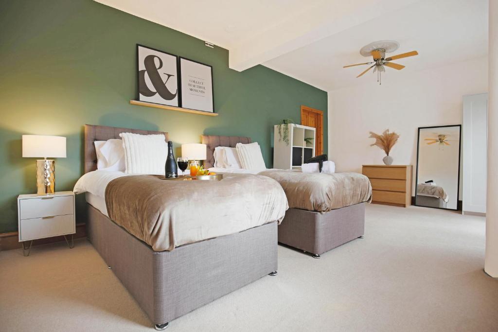a bedroom with two beds and a green wall at Spacious House in City Centre - Sleeps up to 9 - Free Parking, Super-Fast Wifi, Garden, Balcony, and Smart TV with Virgin TV and Netflix by Yoko Property in Northampton