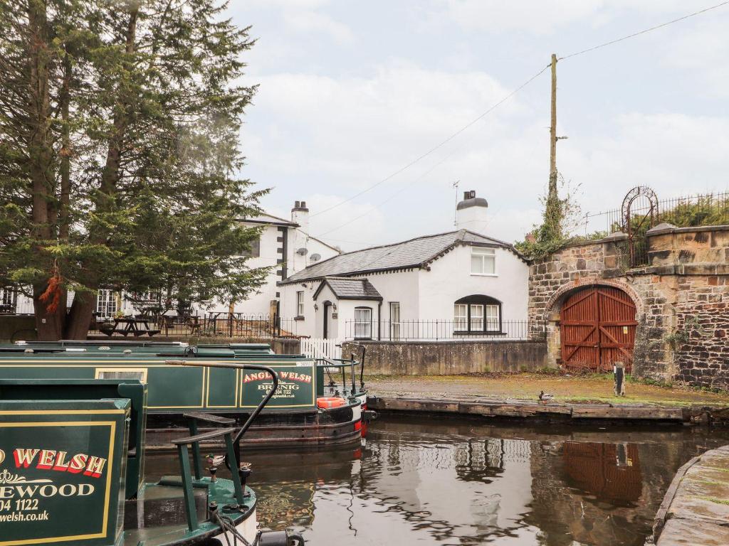 a boat is docked next to a house at Scotch Hall Cottage in Llangollen