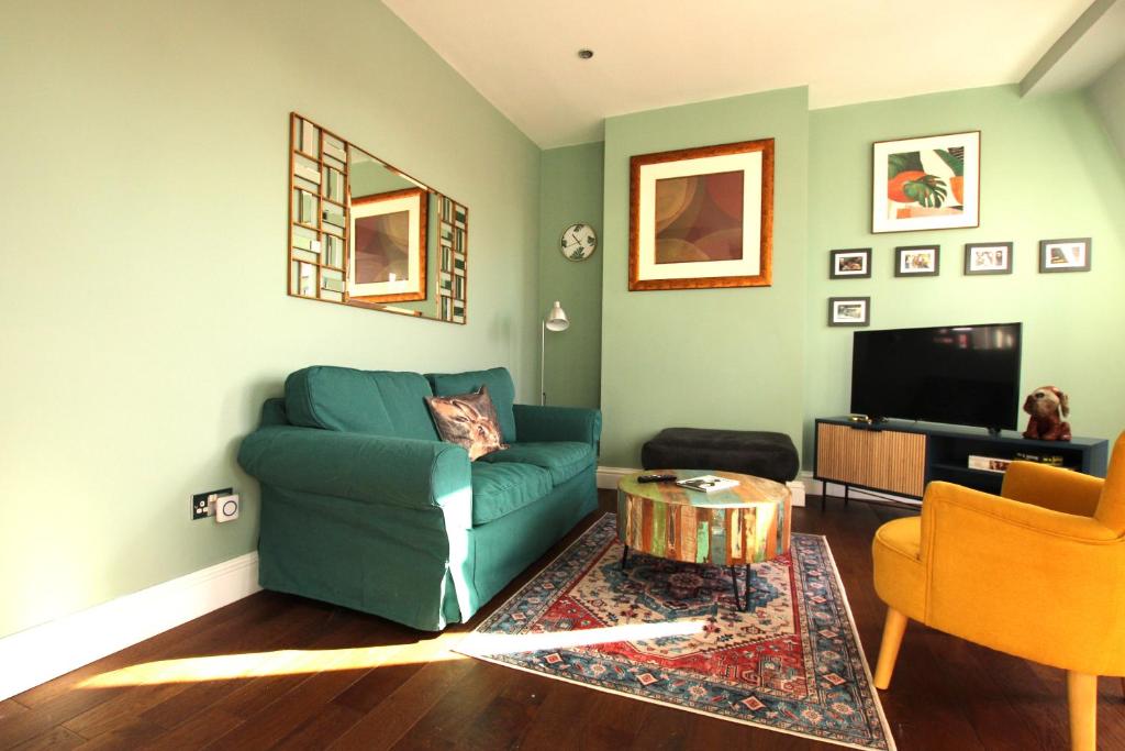 a living room with a blue couch and a tv at Lovely, cosy 3 bedroom apartment in Teddington