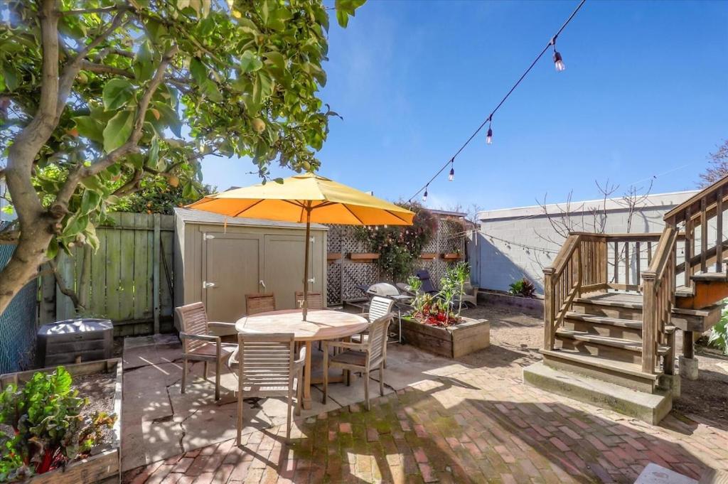 a patio with a table and an umbrella at Light filled Condo with enclosed sunny backyard in Oakland