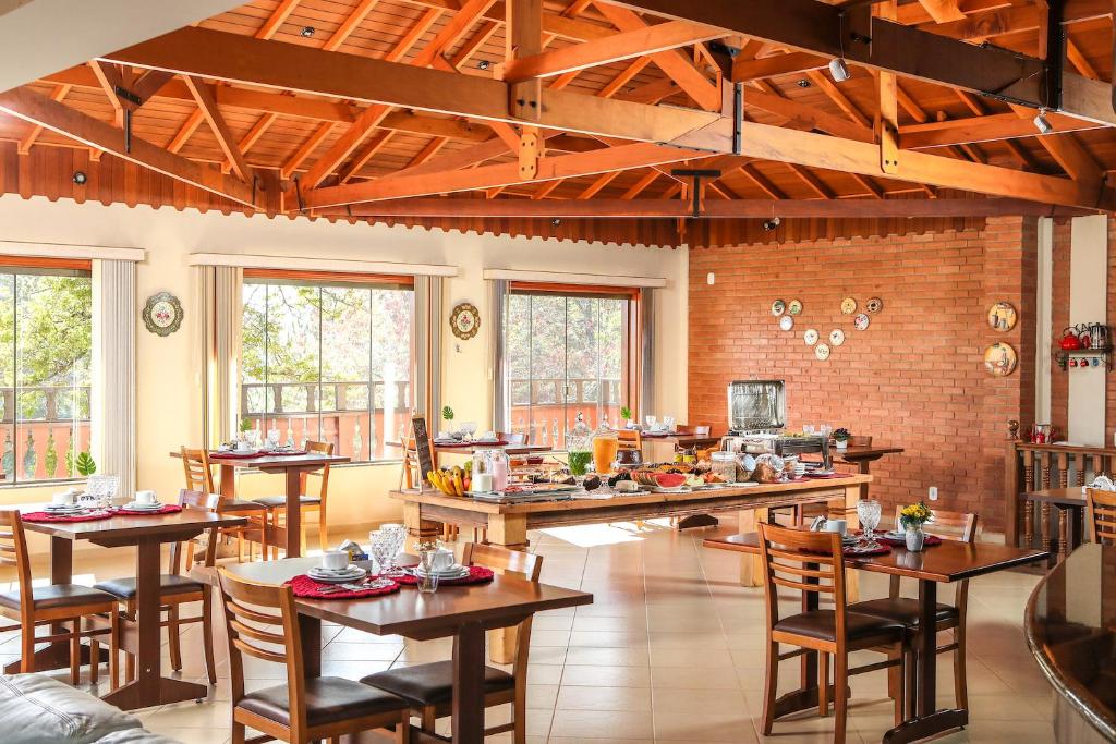 a room with tables and chairs and a kitchen at Pousada Alto de Monte Verde in Monte Verde