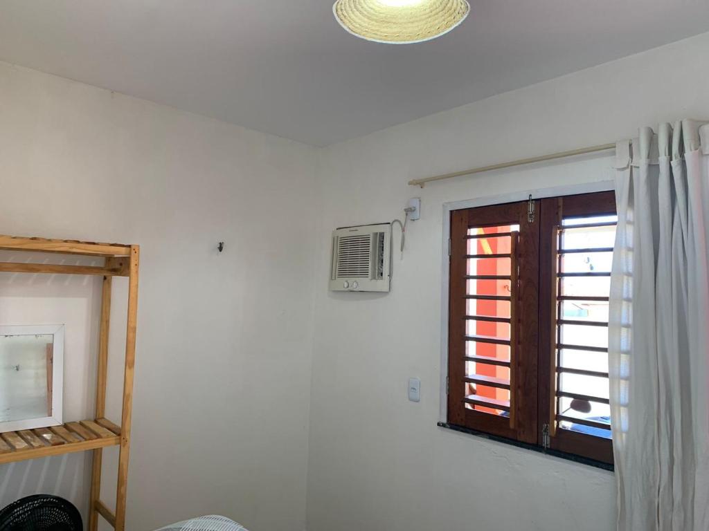 Cette chambre blanche dispose d'une fenêtre et d'un ventilateur. dans l'établissement Chalés Solmar, à Itapipoca