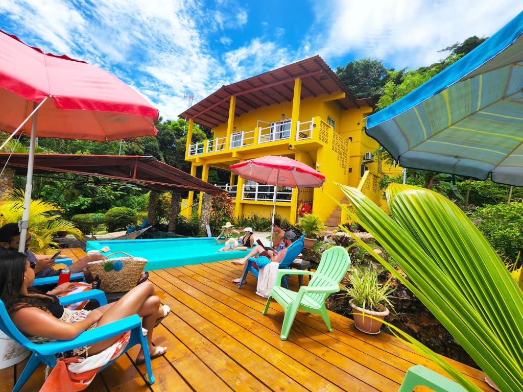 un grupo de personas sentadas en una terraza cerca de una casa en Cerrito Tropical Eco Lodge, en Taboga