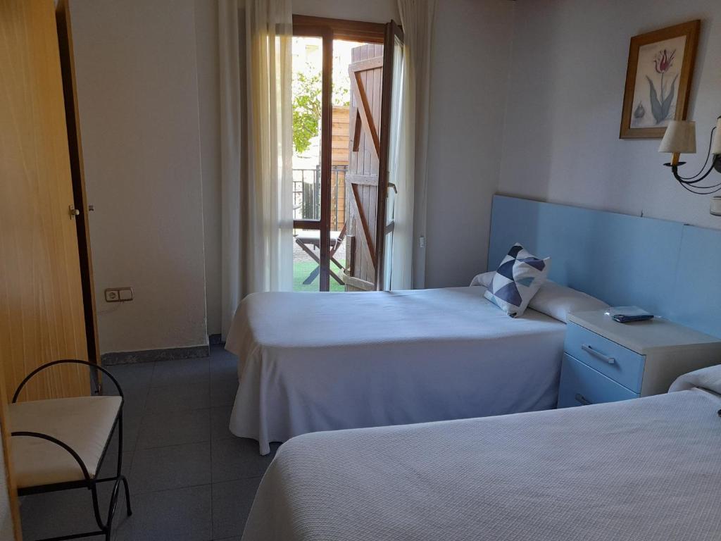 a hotel room with two beds and a balcony at Hostal Casa Juan in Castejón de Sos
