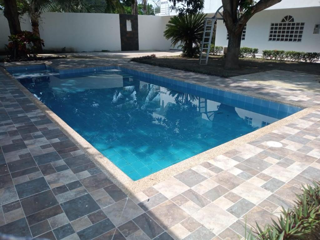 una piscina con acqua blu e pavimento piastrellato di Villa Samari 3 casa campestre con piscina privada a Girardot