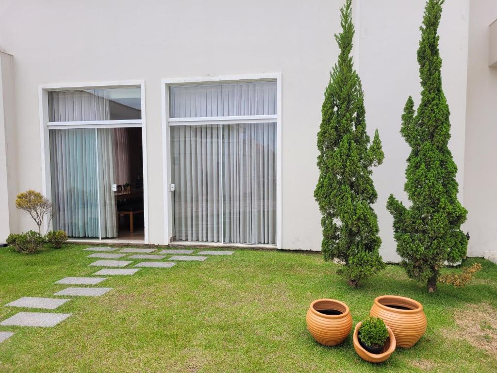 a yard with threeotted plants in front of a house at Apartamento completo no centro de Tijucas 105 in Tijucas