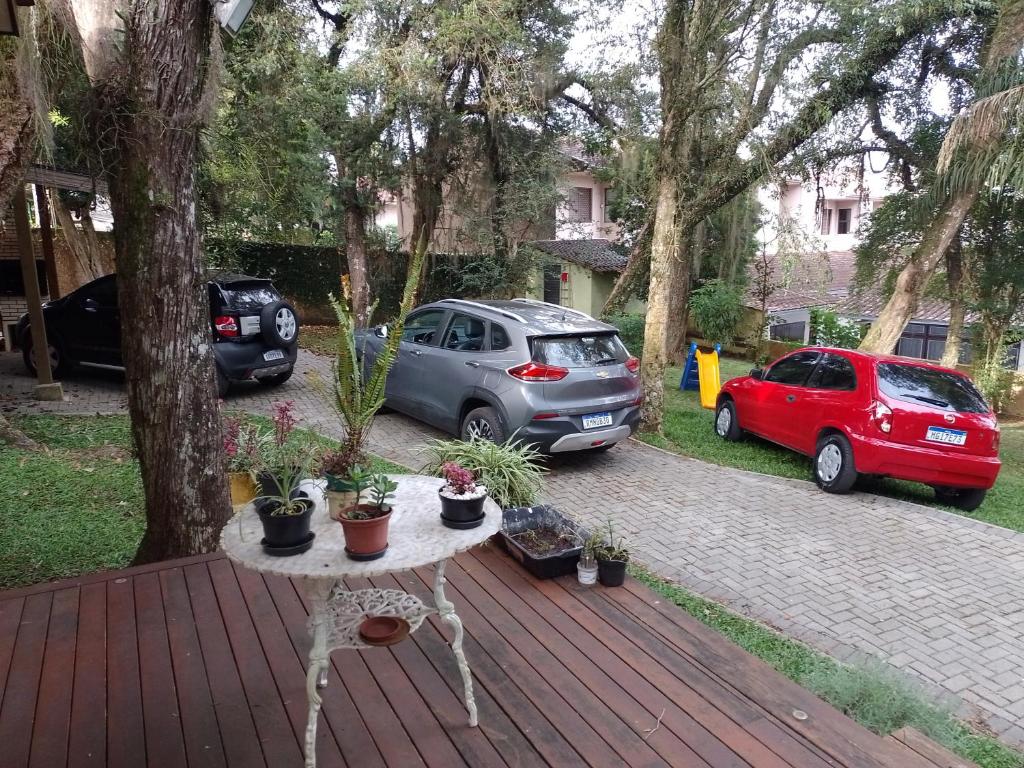 a table with potted plants on a deck with two cars at Charming Home 2 min. from Barigui Park in Curitiba