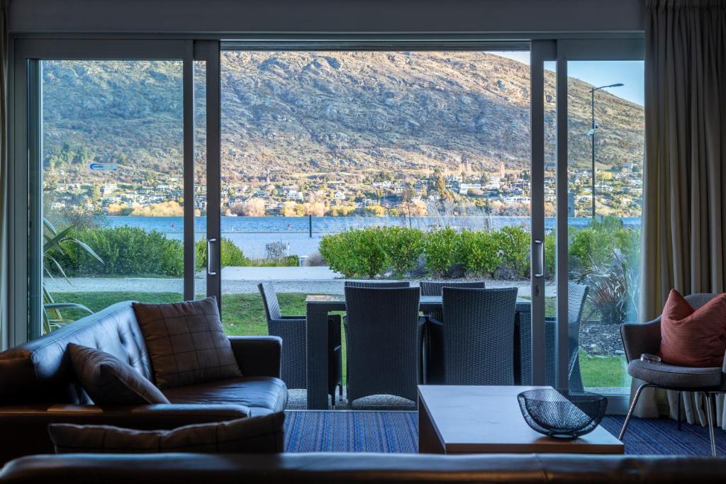 a living room with couches and a large window at Marina Apartments - Element Escapes in Queenstown