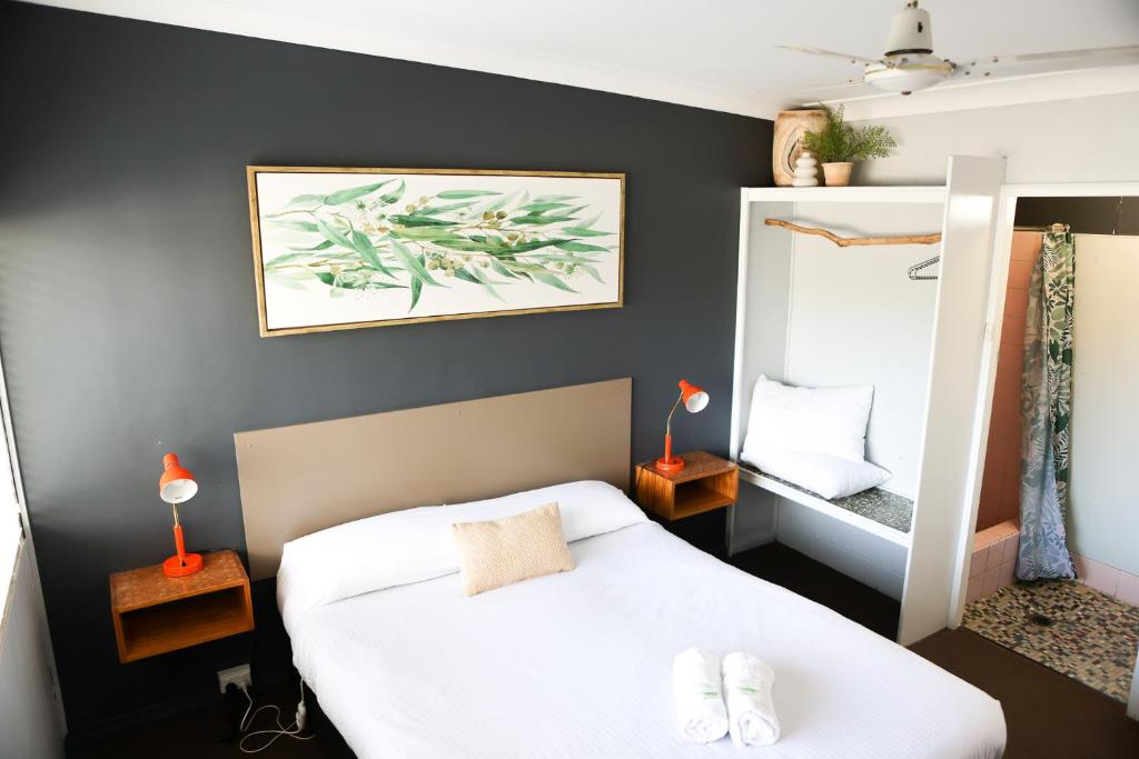 um quarto com uma cama branca e um espelho em Motel Melrose em Mittagong