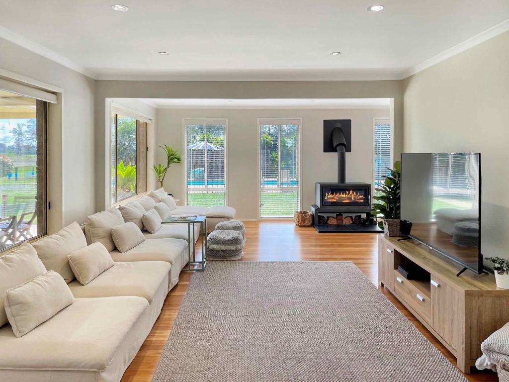 a living room with a white couch and a fireplace at Tallowood House in Nulkaba