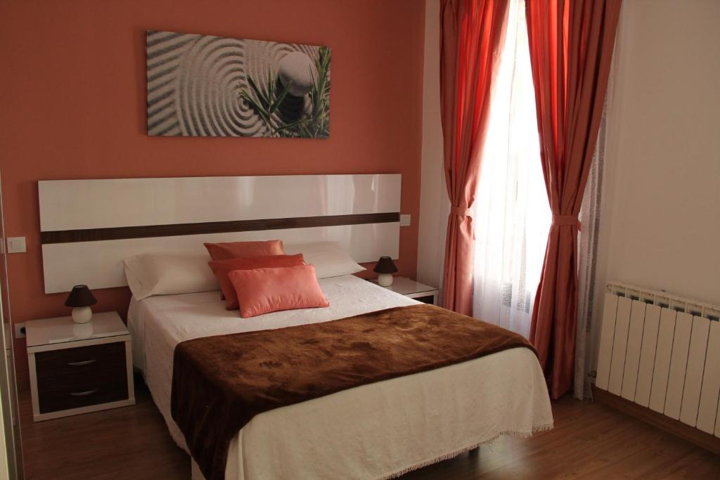 a bedroom with a bed with orange walls and a window at Casa de Huéspedes Galaica in Madrid