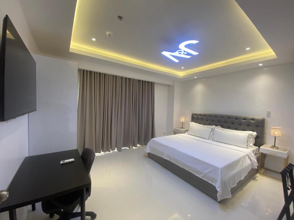 1 dormitorio con cama, escritorio y piano en J&V Hotel and Resort en Apaleng