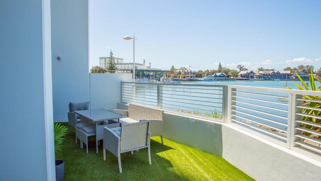 a balcony with tables and chairs and a view of the water at Bridgepoint 103 in Mandurah