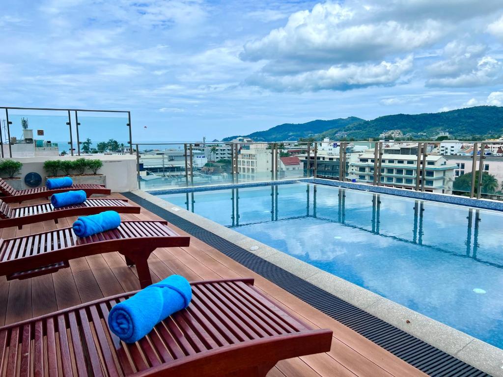 パトンビーチにあるCentro One Patongの木製のベンチとスイミングプールが備わる屋上ホテルです。