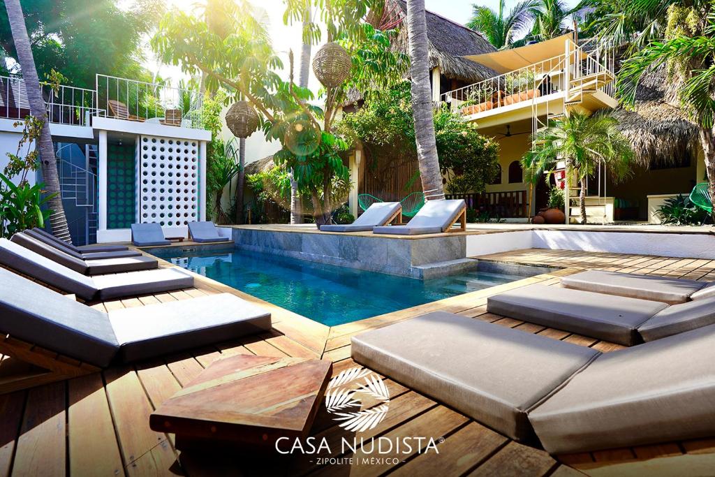 a swimming pool with lounge chairs and a house at Casa Nudista - LGBT Hotel in Zipolite