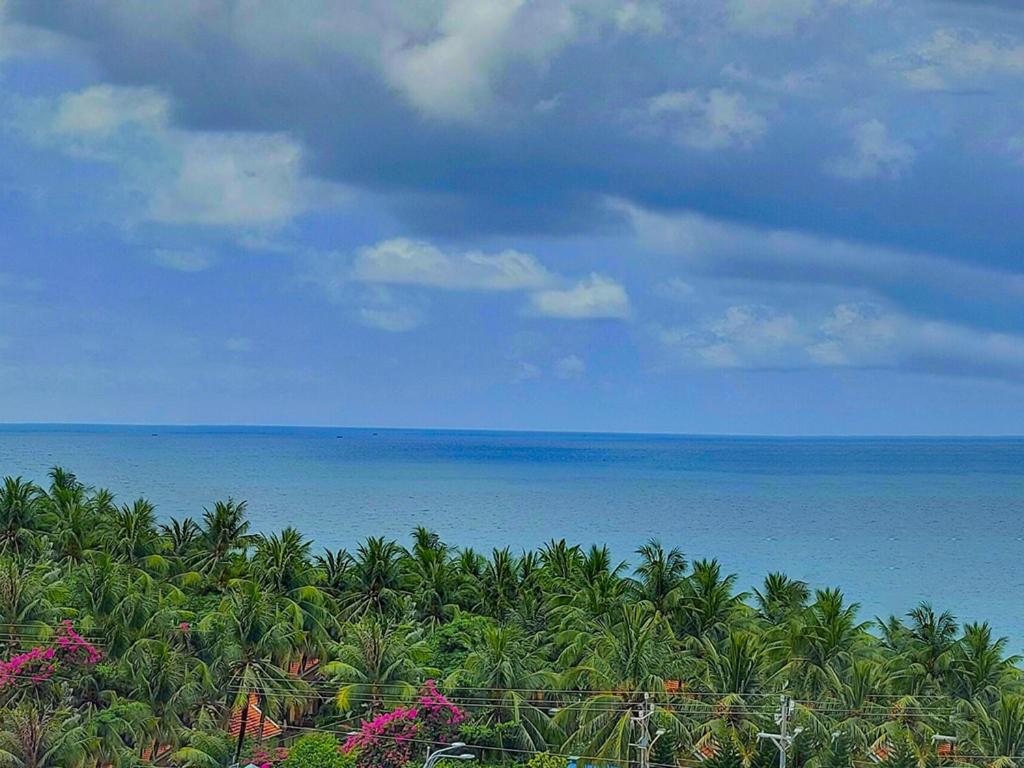 uma vista para o oceano a partir de uma praia com palmeiras em Victoria Phu Quoc hotel 1 minute walking to beach, near to night market em Phu Quoc