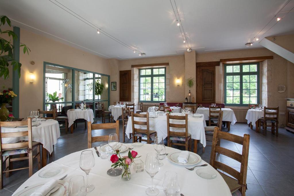 une salle à manger avec des tables et des chaises blanches dans l'établissement Le Lion d'Or, à Manzac-sur-Vern